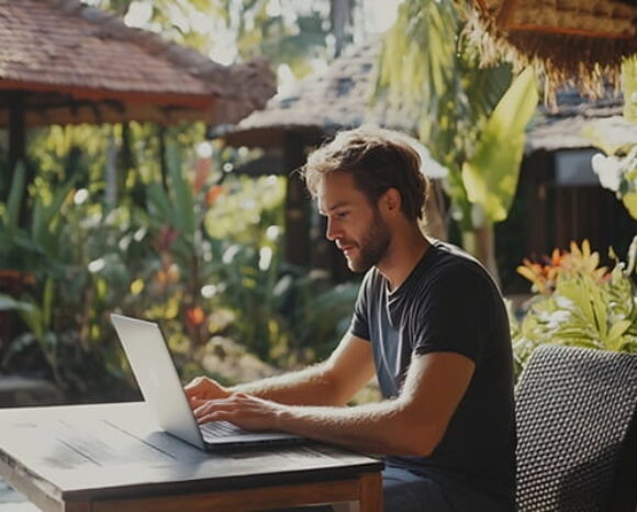 Mann arbeitet am Laptop während Workation im Paradies