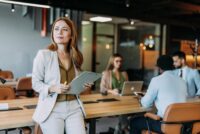 Selbstbewusste junge Business-Frau sitzt auf einem Tisch neben ihrem Team