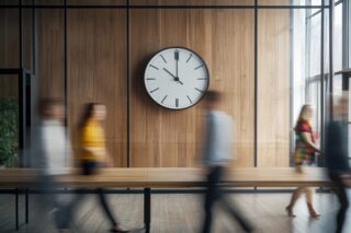 Zeitliche Wahrnehmung: Menschen rennen an Uhr vorbei