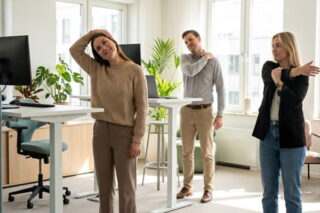 Kollegen machen Dehnübungen im Büro