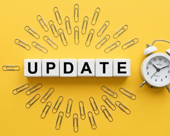 Auf gelbem Untergrund steht in der Mitte Update, umrandet von Büroklammern, neben einem Wecker