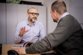 Zwei Männer sitzen am Tisch und besprechen einen Sachverhalt