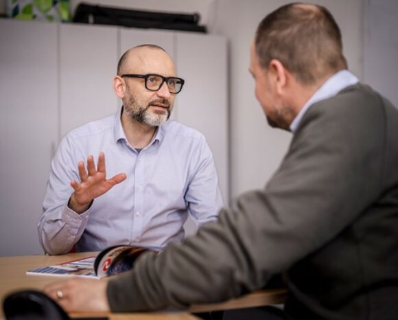 Zwei Männer sitzen am Tisch und besprechen einen Sachverhalt