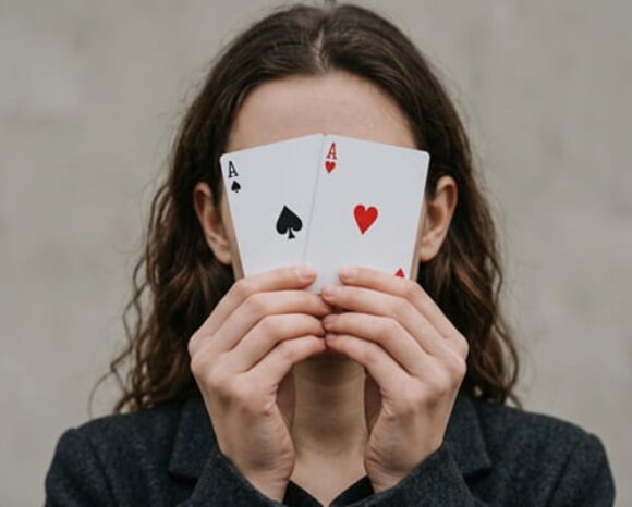 Junge Frau hält zwei Spielkarten vors Gesicht