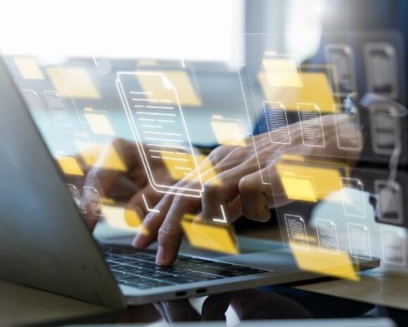 Hände tippen auf einem Laptop, überlagert von schwebenden Symbolen für Ordner und Dokumente – Konzept für Dateiverwaltung, Cloud-Speicher und digitales Dokumentenmanagement.